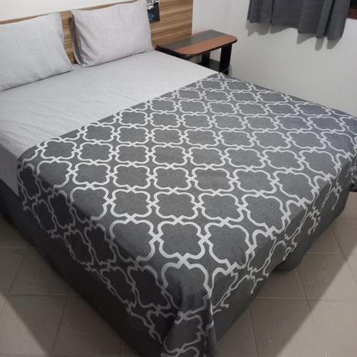 a bed with a black and white comforter at Pousada Parque Suites - Estacionamento e Piscina in Guarujá
