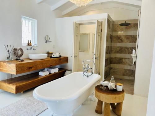 a white bathroom with a tub and a sink at Long Story Guest House in Plettenberg Bay