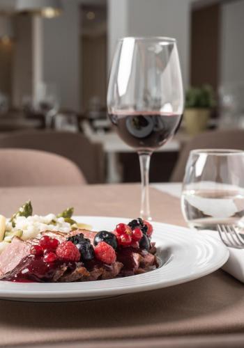 a plate of food on a table with a glass of wine at Essence Inn Marianos Hotel in Fátima