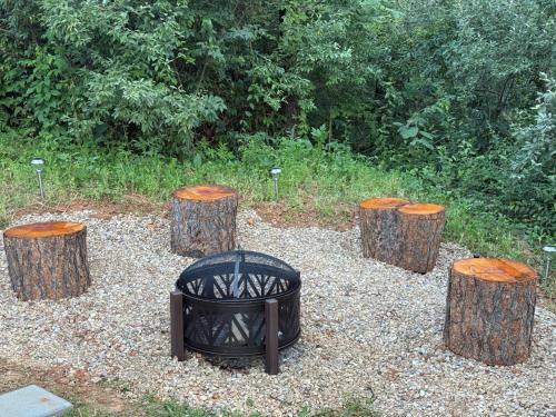 a group of tree stumps with a grill and four logs at The Ancient Bears Den By Avada Properties in Union Grove