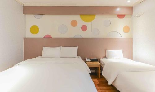 a bedroom with two beds and a wall with polka dots at Yeongjong Stay Hotel in Incheon