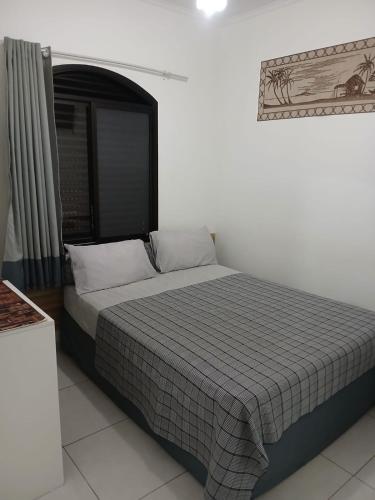 a bedroom with a bed with a checkered blanket at Pousada Parque Suites - Estacionamento e Piscina in Guarujá
