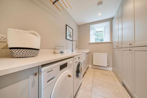 a white laundry room with a washer and dryer at Coach House with Hot Tub in Idyllic Bury St Edmunds 