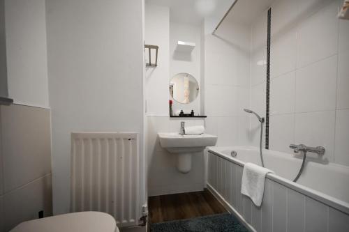 a white bathroom with a sink and a bath tub at Blue Diamond in Milton Keynes