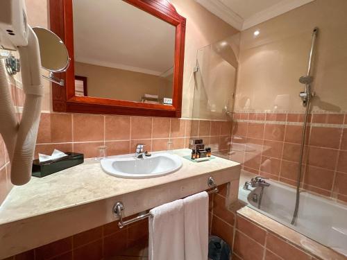 a bathroom with a sink and a mirror and a tub at Grand Mogador Agdal & Spa in Marrakech