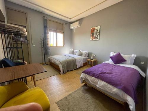 a bedroom with two beds and a table at Palms Garden in Erfoud