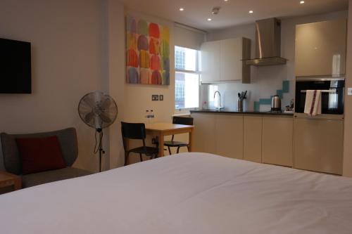 a bedroom with a white bed and a kitchen at The Alma Rooms in London