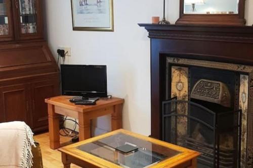 a living room with a fireplace with a tv and a table at Cosy Townhouse on The Hill in Ireland in Banagher