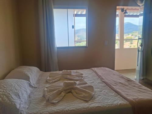 a bed with a ribbon on it with two windows at Casa de Luz - Lar na Serra - Suite - Duplo ou Triplo - N4 in Miguel Pereira