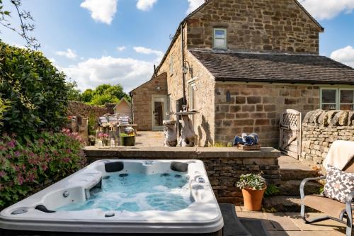 a hot tub in the backyard of a stone house at Heather Cottage in Kirk Ireton