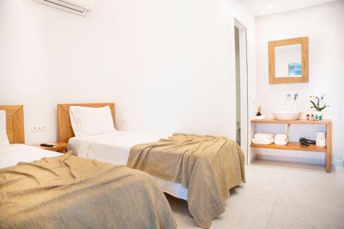 a hotel room with two beds and a mirror at Due Mari Mykonos in Agios Ioannis Mykonos