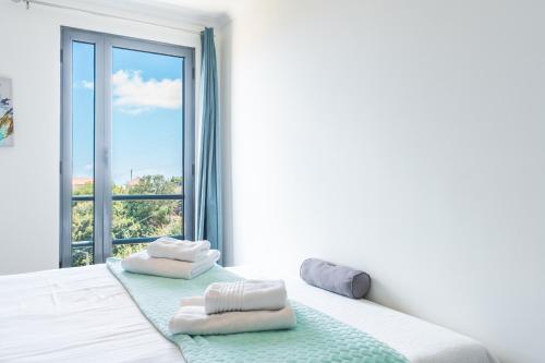 een witte slaapkamer met een raam met handdoeken op een bed bij Vista Mar by Atlantic Holiday in Caniço