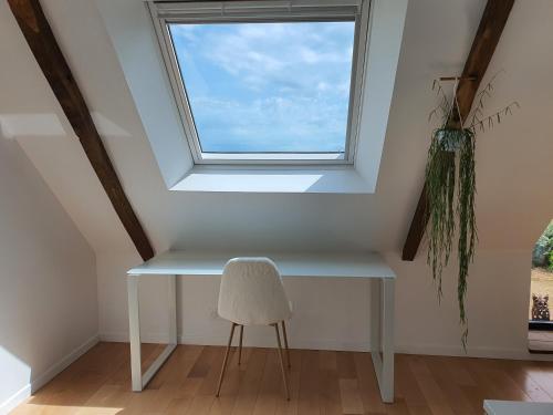 a white table and a chair in a room with a window at Maison De Campagne Proche de La Mer in Brandérion