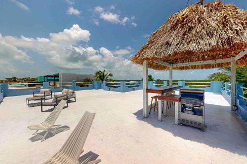 a bar on the beach with a straw umbrella and chairs at Villa 19 at Mara Laguna in San Pedro