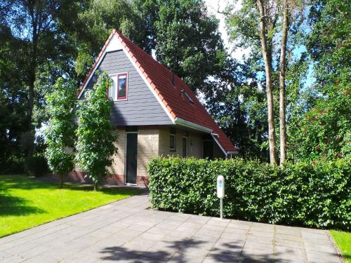 a small house with a red roof in a yard at Holiday Home near Sallandse Heuvelrug in Lemele