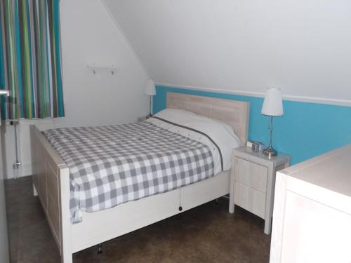 a small bedroom with a bed and a blue wall at Holiday Home near Sallandse Heuvelrug in Lemele