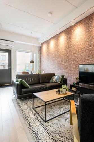 a living room with a leather couch and a brick wall at City Home Alvari, jäähdytys, ilmainen pysäköinti autohallissa in Kuopio