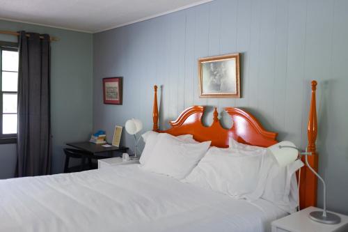 a bedroom with a large white bed with an orange headboard at The Little Lion in Great Barrington
