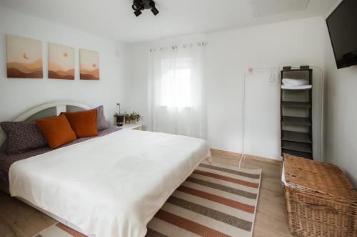 a bedroom with a large white bed with orange pillows at Panorama Lugasu in Lugaşu de Jos
