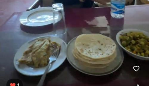 a table with a plate of food and a bowl of peas at Nishorgo Nirob Eco Resort in Sreemangal