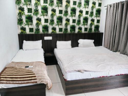 two beds in a room with a wall with plants at HOTEL RAMANAND PALACE UJJAIn in Ujjain