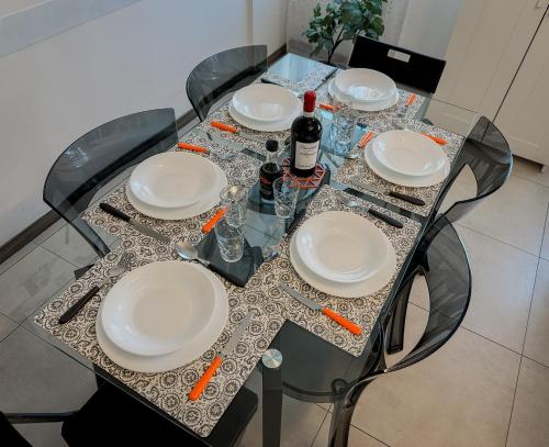 a glass table with plates and bottles of wine on it at Design Moderno - Appartamento Centrale con 2 Suite in Turin