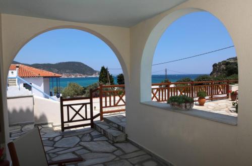 a room with two arched windows and a view of the ocean at Pleoussa Studio and Apartments in Skopelos Town