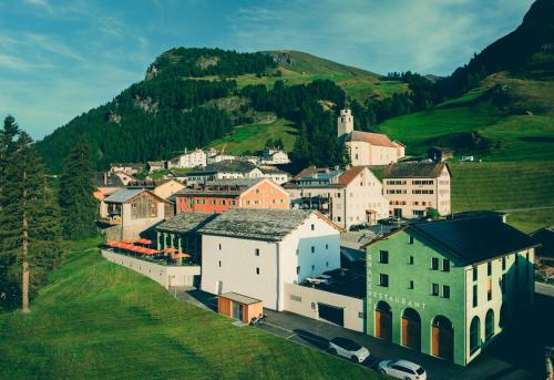 a town on a hill with a mountain in the background at Speluca Brauerei & Genusshotel - Self-Check-in in Splügen