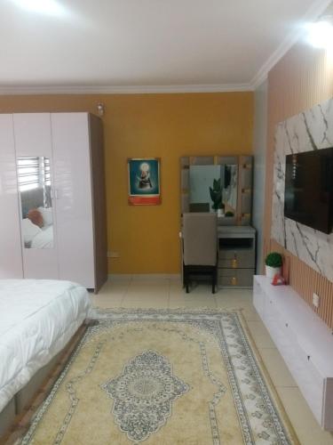 a bedroom with a bed and a desk and a tv at Ensuit Apartment in Ibadan