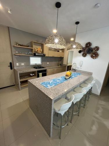 a kitchen with a counter with chairs and a island at Reserva Del Mar Apartamentos in Gaira