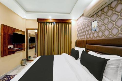 a bedroom with a large bed and a mirror at Super Townhouse OAK The Dev Regency in Patna