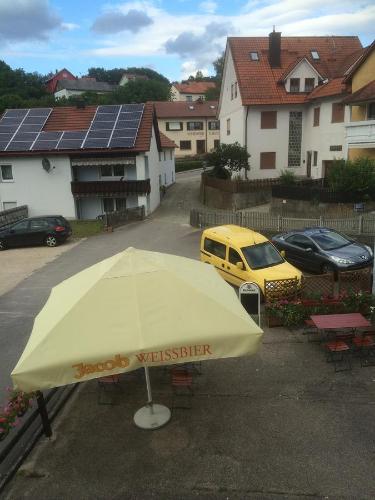 a yellow umbrella in a parking lot with some cars at Zur Krone in Wolfsegg