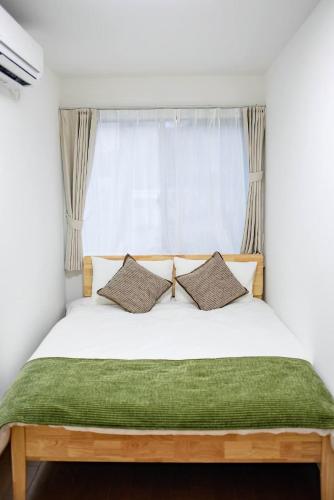 a bed with two pillows in front of a window at Osaka Purestay 5 rooms 2 parking spaces two balconies 8-11 人 Wi-Fi 玉出西 天下茶屋 心斎橋 道頓堀 近い 一 戸建 in Osaka