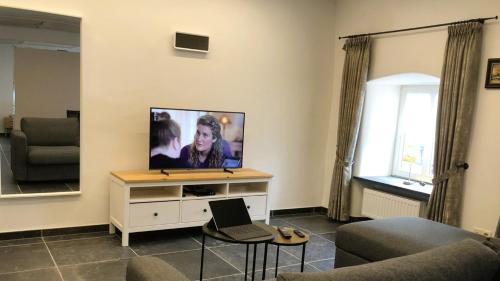 a living room with a flat screen tv on a wall at POSTRELAIS ARDENNES "Suite 1779" in Burg-Reuland