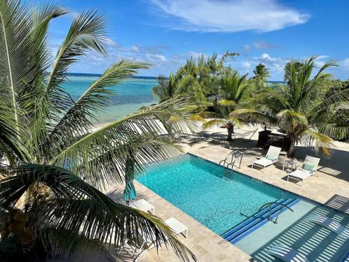 ein Swimmingpool mit Palmen und dem Meer in der Unterkunft The Sunrise at Cottages in Sand Bluff