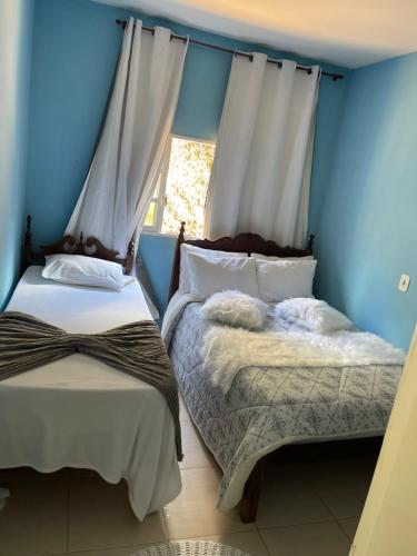 2 Betten in einem Zimmer mit blauen Wänden und einem Fenster in der Unterkunft casa temporada pedra azul in Domingos Martins
