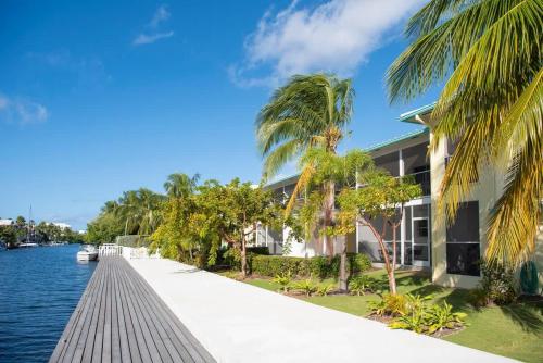 a house next to the water with palm trees at Snug Harbour View Condo #7 in George Town