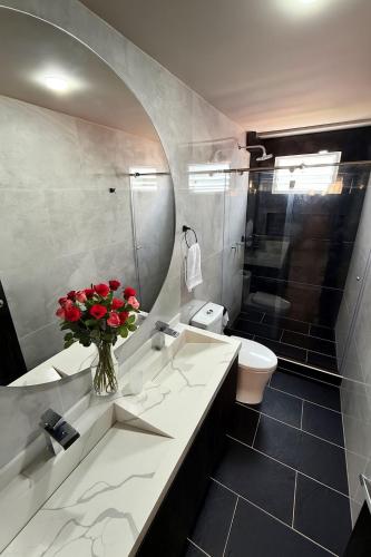 a bathroom with a sink and a toilet and a vase of flowers at Luz Y Diseño in Santa Rosa de Cabal