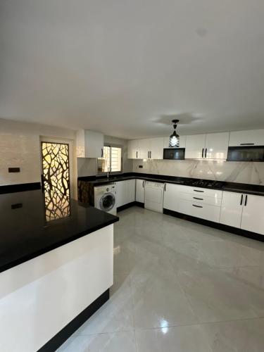 a large kitchen with white cabinets and black counter tops at Villa Kenitra in Kenitra