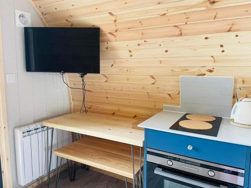 a room with a desk with a television on a wall at Beach House Pods in Dunoon