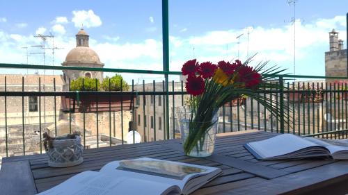 a table with a vase of flowers and a book at Attico Barocco in Lecce