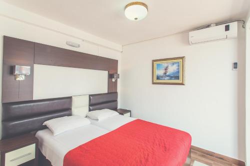 a bedroom with a red and white bed in it at David apartments and rooms in Dobra Voda