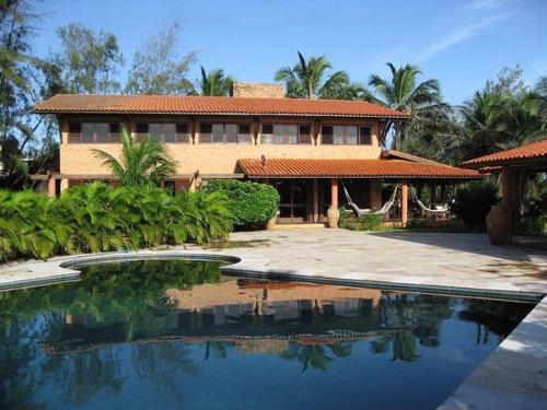 una casa con piscina frente a una casa en Mansao Santa Rita, en Cumbuco