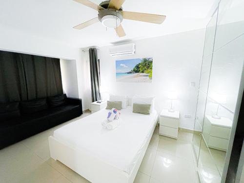 a white bedroom with a bed and a ceiling fan at LOS CORALES Resort VILLAS & Apartments WIFI BEACH Club & SPA in Punta Cana