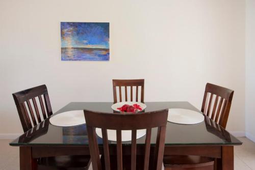 a dining room table with four chairs and a painting at Snug Harbour View Condo #9 in George Town