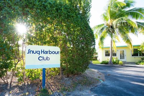 a sign in front of a house with a palm tree at Snug Harbour View Condo #9 in George Town
