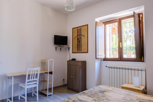 a bedroom with a bed and a desk and a window at Dentro le mura, natura relax e cultura in LʼAquila