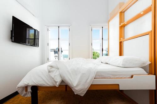 a bedroom with a bed with a tv and windows at Hotel AtypiQ in Quebec City