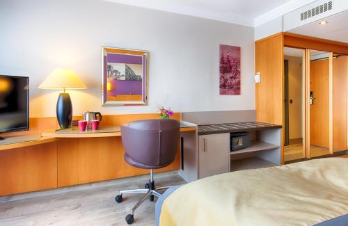 a hotel room with a bed and a desk and a chair at Leonardo Royal Hotel Köln - Am Stadtwald in Cologne
