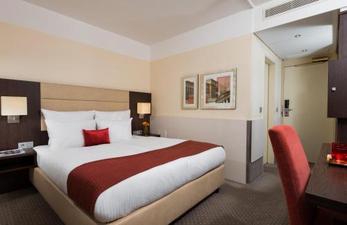 a hotel room with a large bed and a desk at Leonardo Hotel Munich Arabellapark in Munich